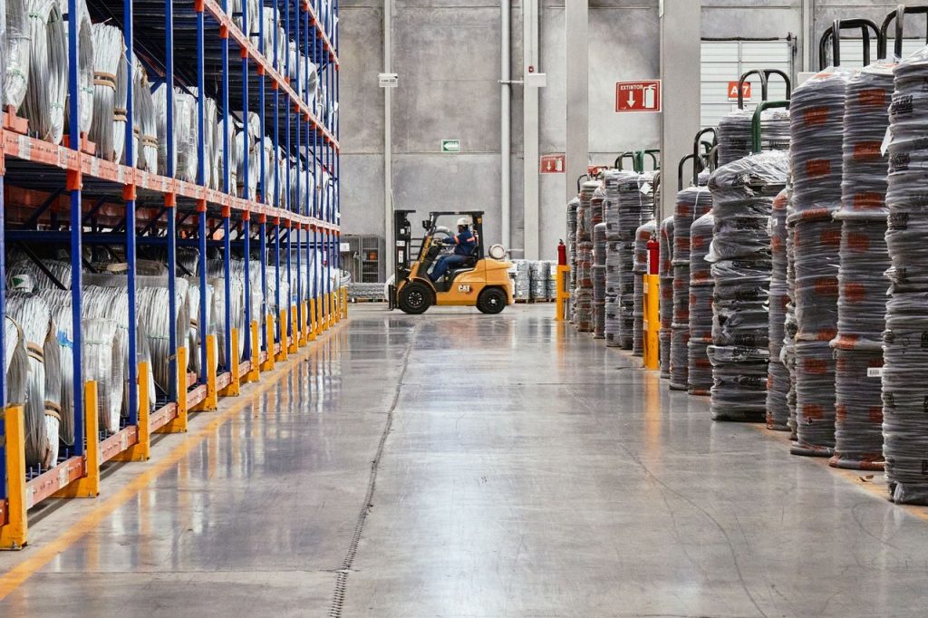 Empilhadeira movimenta mercadorias empilhadas em um armazém industrial.
