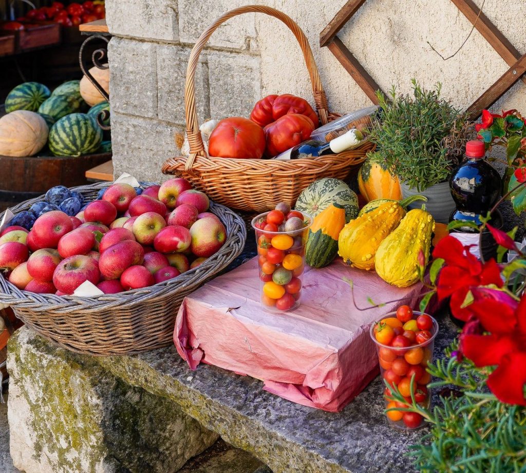 Do campo à assistência: PAA organiza nova rota para alimentos em Campo Grande Variedade de frutas e hortaliças frescas expostas em uma feira ao ar livre.