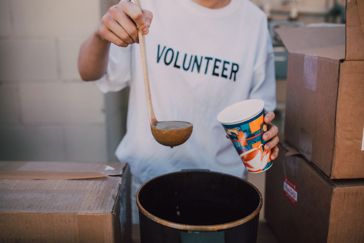 Voluntário serve sopa a pessoas durante uma ação comunitária de assistência social.